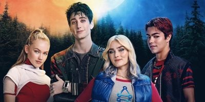 Four teenagers stand together in front of a forest, illuminated by warm orange and cool blue light. Their distinct clothing and colorful hairstyles reflect the vibrant world of Disney’s ZOMBIES 4: Dawn of the Vampires.