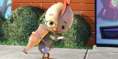 An animated chicken, reminiscent of Chicken Little from the cancelled Disney TV series, wears green glasses and a makeshift vest with a large bottle tied to its back, standing on a sidewalk and glancing backwards. Bushes and a brick wall are in the background.