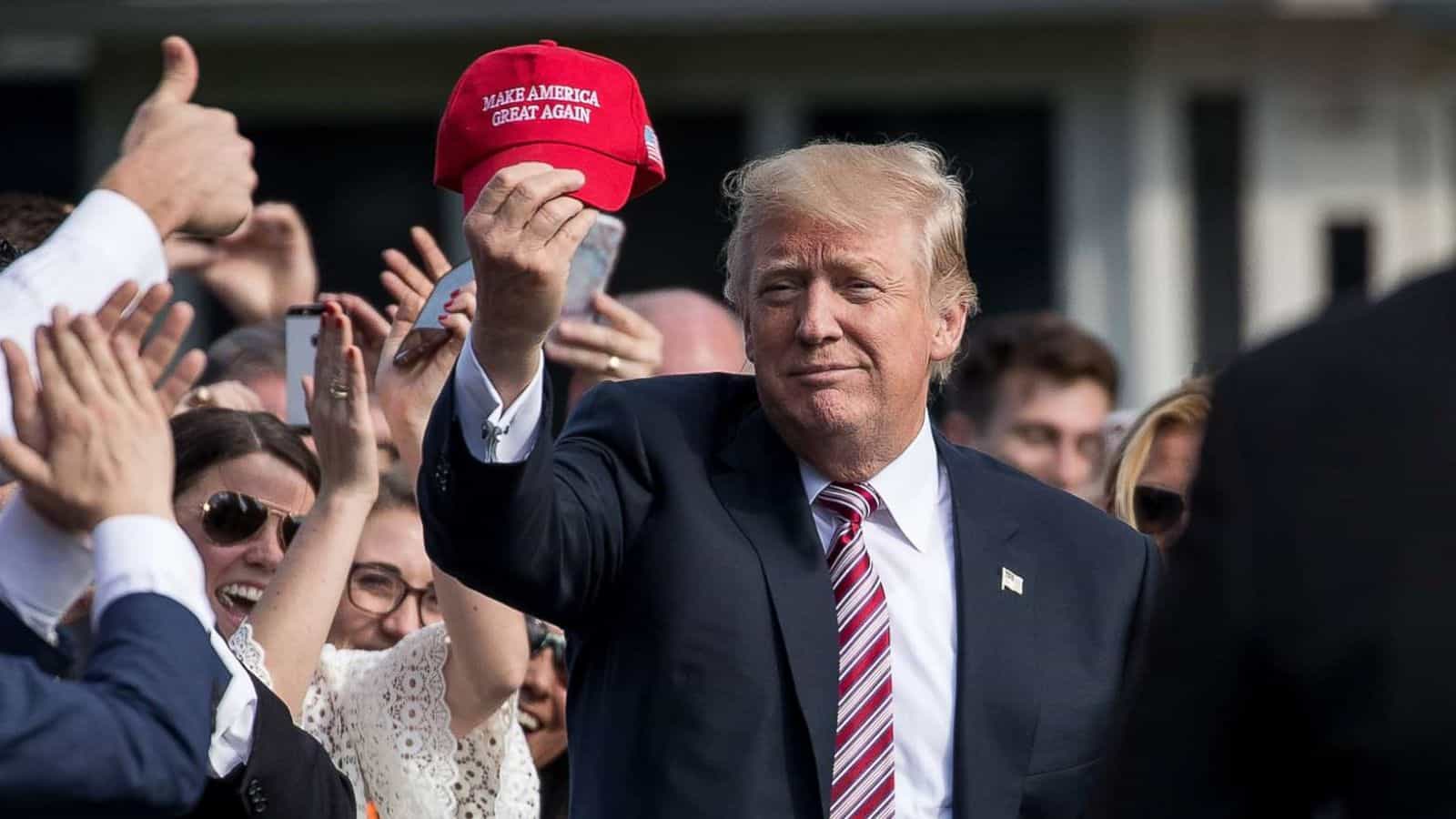 Donald Trump holds a MAGA hat