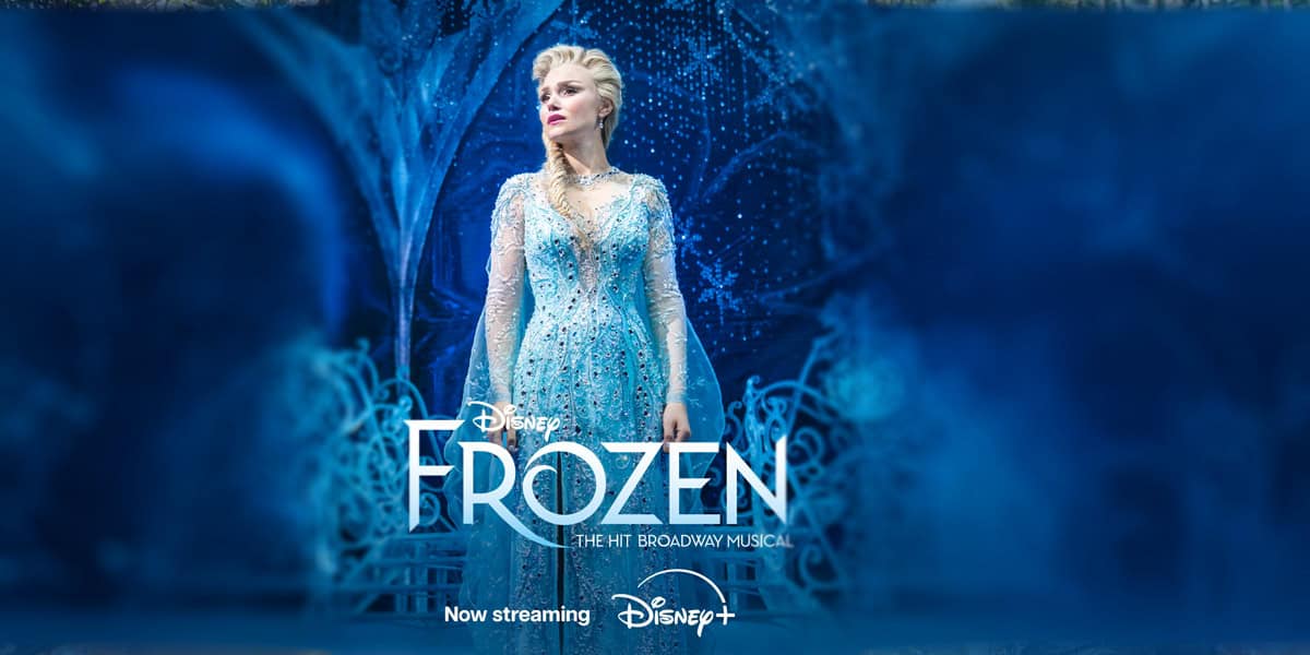A woman dressed as Elsa in a sparkling blue gown stands confidently on a stage surrounded by icy, blue scenery. The text reads: "Frozen The Broadway Musical – the hit Broadway show now streaming on Disney+.