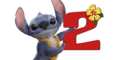 Stitch, the lovable blue alien from Disney’s Lilo & Stitch, stands smiling and holding a large red number 2 with a yellow hibiscus flower on it, celebrating the excitement of his live-action adventures.