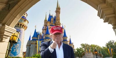 Donald Trump wears a MAGA hat in front of Cinderella Castle