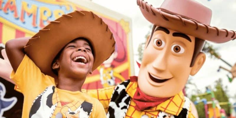A young boy smiles next to Woody in Toy Story Land at Disney's Hollywood Studios