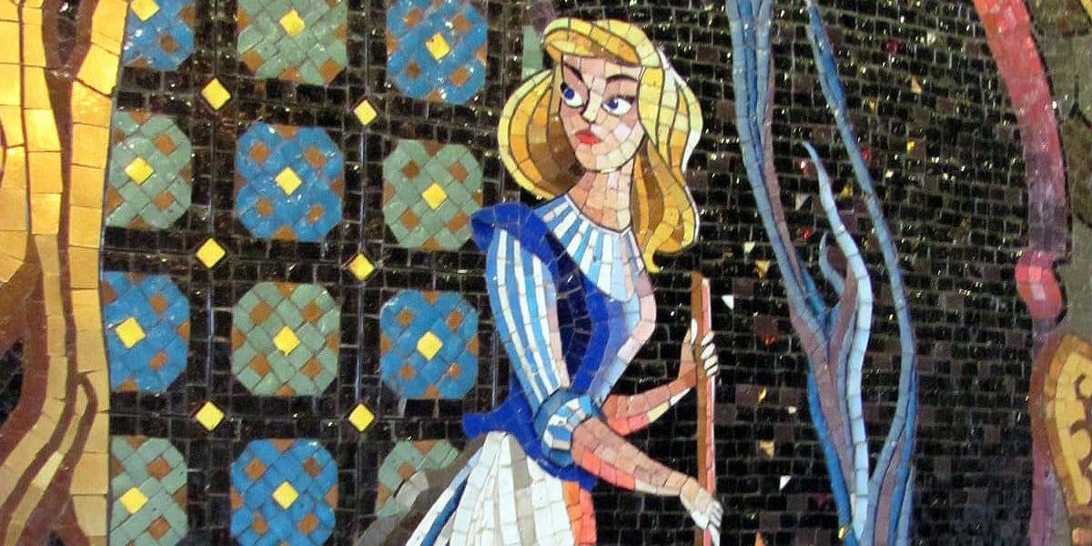A colorful mosaic depicts a blonde woman in a blue and white dress holding a broom, surrounded by intricate geometric and floral patterns.