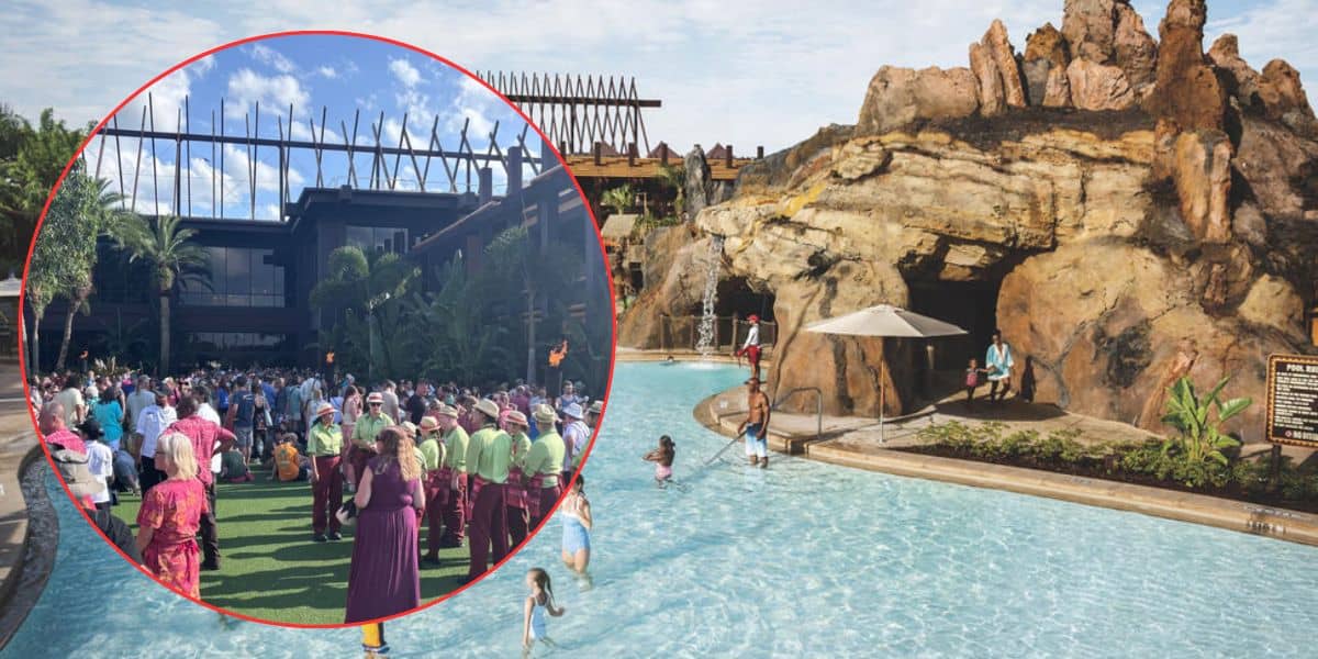 A crowd gathers on a lawn near a resort building, while people swim and play in a large pool with a rocky waterfall feature nearby. The scene is sunny and tropical.