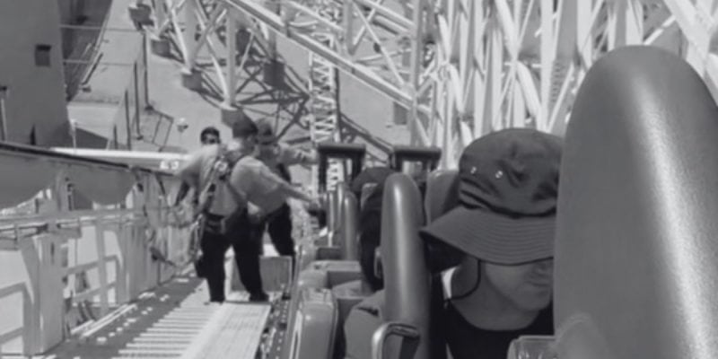 A black and white photo shows people stuck on the Incredicoaster as cast members help them evacuate.