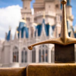 A close-up of the iconic Sword in the Stone with Cinderella Castle in the background