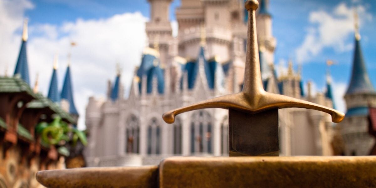 A close-up of the iconic Sword in the Stone with Cinderella Castle in the background