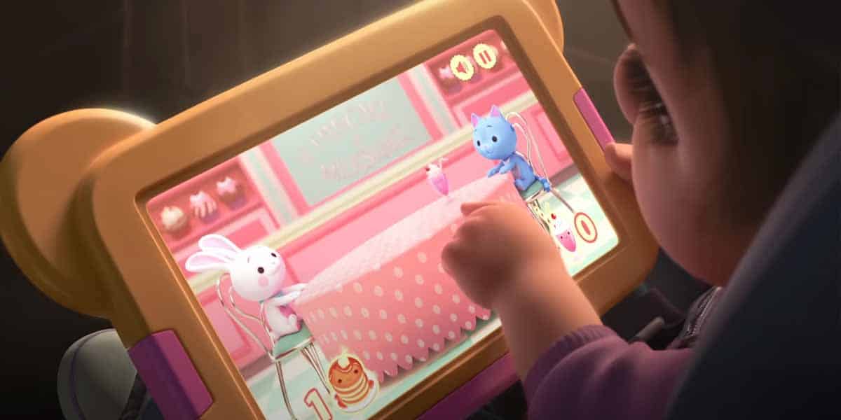 A child plays a game on a tablet with a yellow bear-shaped case, touching the screen where LilyPad, a new character, sits with a white bunny and blue creature at a pink table in a colorful virtual café.