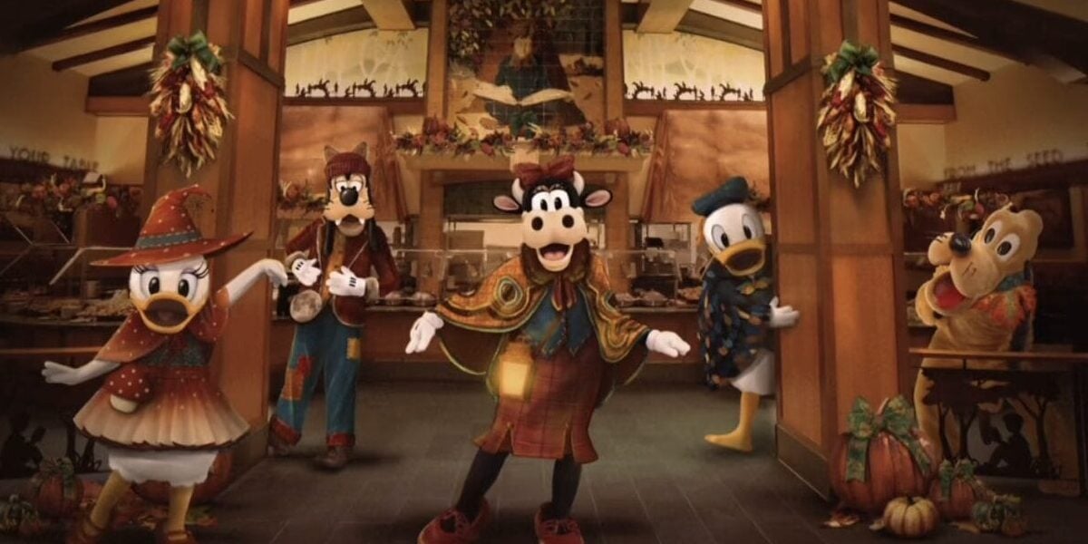 Daisy Duck, Goofy, Clarabelle Cow, Donald Duck, and Pluto, all in autumn-themed outfits, stand in a festively decorated room with pumpkins and hanging lanterns at the Disneyland Halloween Buffet at Storyteller's Cafe