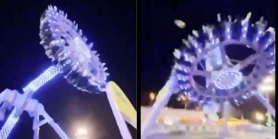A brightly lit amusement park ride spins upside down at night, with passengers seated in a circular arrangement. The ride, safely illuminated with blue and white lights against a dark sky, shows no signs of a theme park accident.