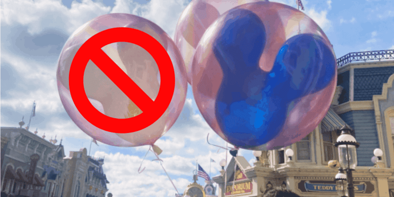 Three balloons float in the air at a theme park; one has a red "no" symbol over it, while another features a blue Mickey Mouse-shaped design. Buildings, flags, and clouds form the backdrop—highlighting some lesser-known Disney World rules.