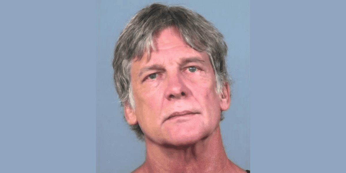 A middle-aged Florida man with short, tousled gray hair and blue eyes stares directly at the camera against a plain, light blue background.