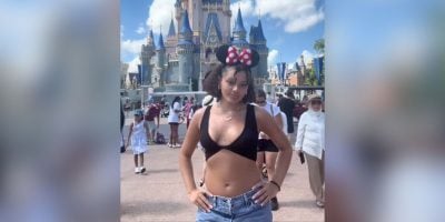 A young woman in front of Cinderella Castle in the shirt that violated the Disney dress code.