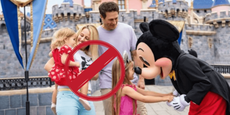 A family with two young children meets a person in a Mickey Mouse costume at Disney World, but the image has a large red prohibition sign over it.
