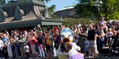 A costumed character, Daisy Duck, intercepts a child who walked into a moving Disney parade.
