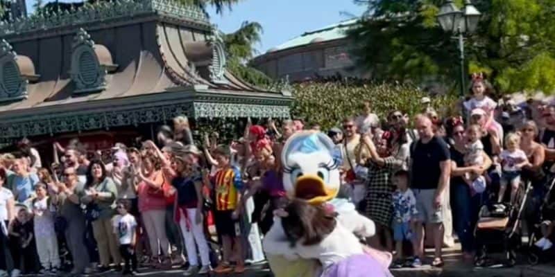 A costumed character, Daisy Duck, intercepts a child who walked into a moving Disney parade.