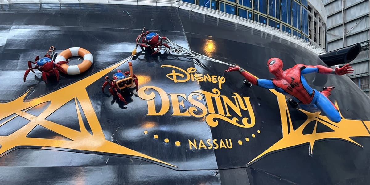 Colorful Spider-Man and spider-robot figures cling to the hull of the Disney Destiny ship, decorated with gleaming gold letters. The Marvel Spider-Bots hold a lifebuoy, rope, and other gear.