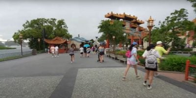 People walking in the China World Showcase Pavilion at EPCOT. It is beginning to rain.