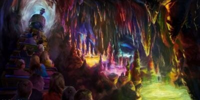 People ride a train through a colorful, glowing cave on Big Thunder Mountain, where vibrant stalactites and stalagmites rise above pools of illuminated water reflecting rainbow-like lights on the rocky walls.