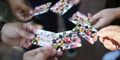 Several hands hold Disneyland tickets featuring cartoon characters like Mickey Mouse and Minnie Mouse, with the tickets overlapping in the center—capturing the magic that inspired Walt Disney animatronic wonders throughout the park.