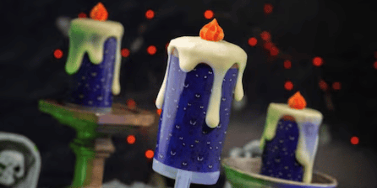 A cake decorated to look like a purple candle with melting white wax and a flame-shaped top, perfect for a Halloween party, set against a dark background with red lights and spooky decor.
