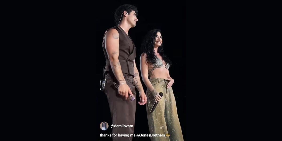 Two singers stand on stage holding microphones, smiling. One wears a sleeveless brown outfit, the other—a sparkling gold top and pants. Text at the bottom reads, “thanks for having me @JonasBrothers. Camp Rock 3 reunion vibes!”.