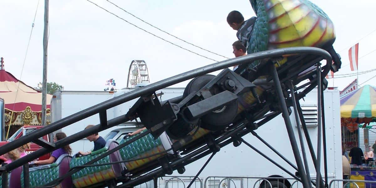 Children ride a small dragon-themed roller coaster at a fair, similar to the one involved in a recent accident.