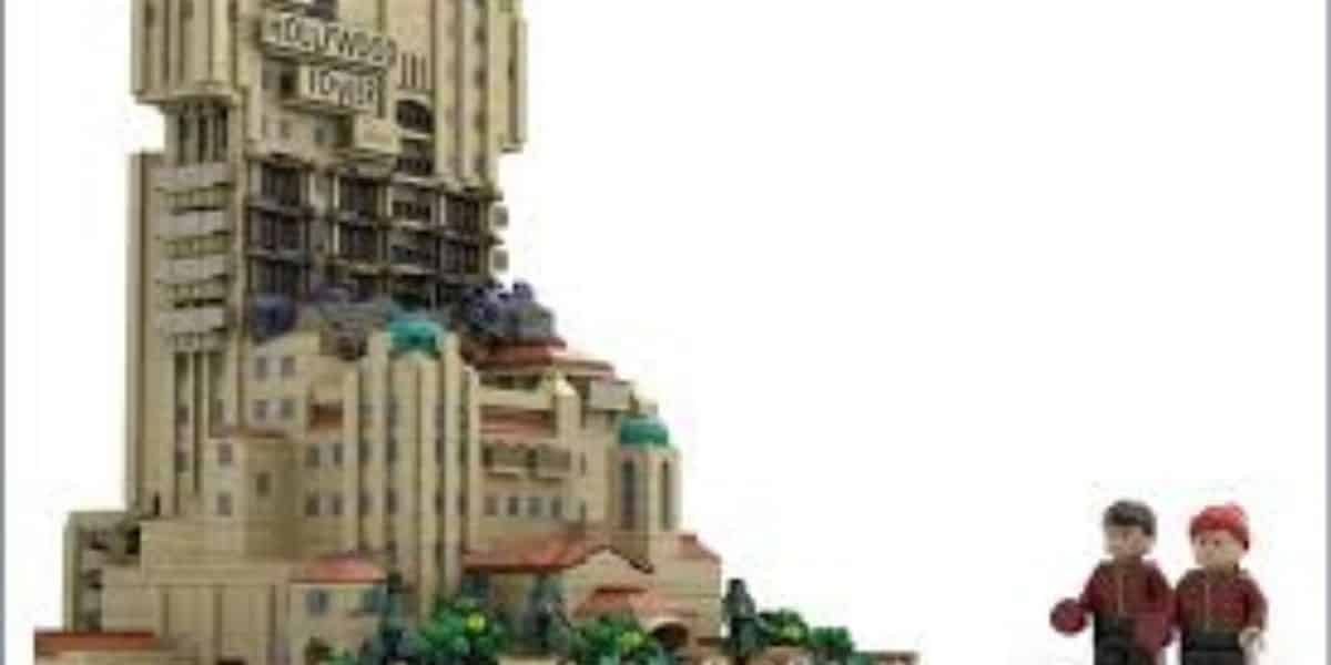 A LEGO model of the Hollywood Tower Hotel stands tall, with two LEGO minifigures in red uniforms positioned nearby on the right.