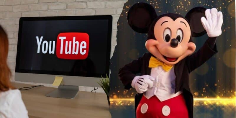 A person sits at a desk facing a computer with the YouTube logo on the screen. Next to the monitor is an image of Mickey Mouse dressed in a tuxedo, smiling and waving as Disney is hit with multiple lawsuits.
