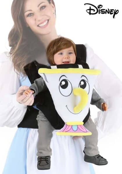 A smiling woman holds a baby in a front carrier designed to look like Chip, the teacup character from Disney’s “Beauty and the Beast.” The unique Disney Costumes-inspired design stands out, with the Disney logo in the top right corner.