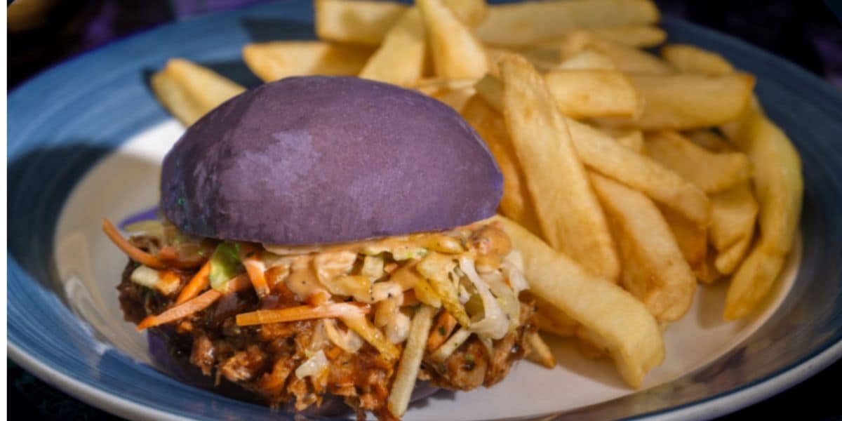 A plate with golden French fries and a Disney-inspired burger featuring a purple bun, filled with shredded vegetables and what appears to be shredded meat.