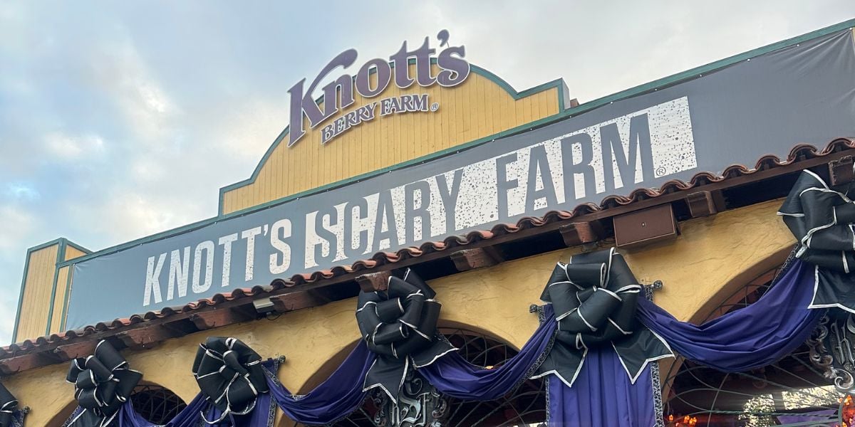 Entrance to Knott’s Scary Farm, decorated with large black bows and purple fabric, featuring a sign with the event’s name under the Knott’s Berry Farm logo.