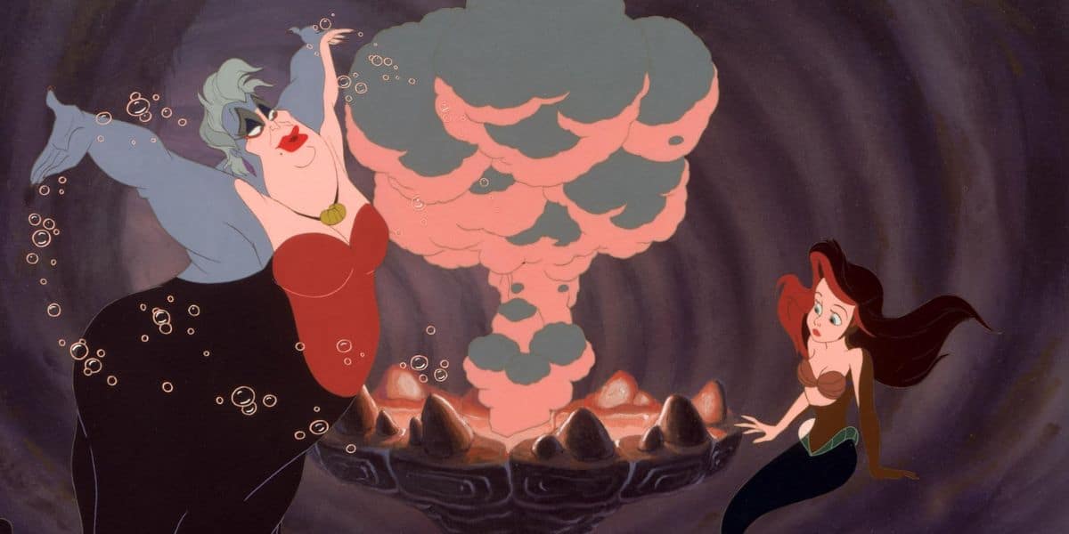 A sea witch, one of the ocean’s most cunning villains, with gray skin and white hair gestures dramatically near a bubbling, smoky cauldron, while a red-haired mermaid looks on with concern in an underwater cave.