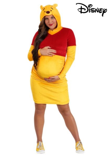 A pregnant woman in a yellow and red Winnie the Pooh costume, smiling and holding her belly, stands against a white background with the Disney logo in the top right corner—perfect inspiration for Disney Costumes lovers.