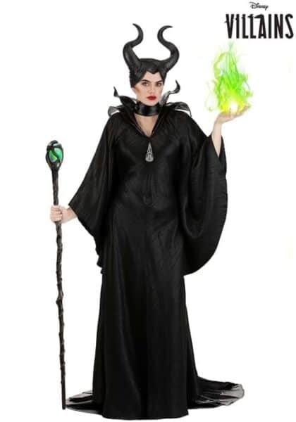 A woman dressed as Maleficent in a black robe with horns, holding a staff in one hand and conjuring green flames with the other. "Disney Villains" text is in the top right corner, perfect for fans of Disney costumes.