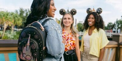 Three women at Disney with one wearing a Loungefly