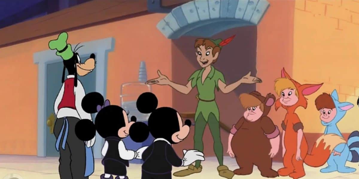 Goofy, Mickey, and Minnie stand facing Peter Pan and children dressed as the Lost Boys in animal costumes, all inside a bright animated House of Mouse room with a stone arch and water cooler in the background.