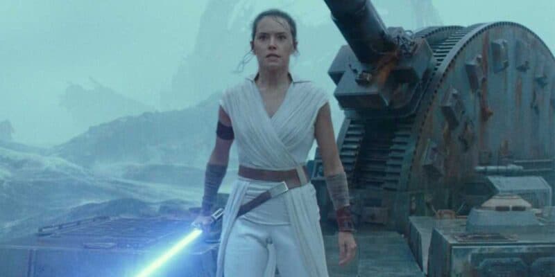 Rey (Daisy Ridley) standing in a storm with a blue lightsaber