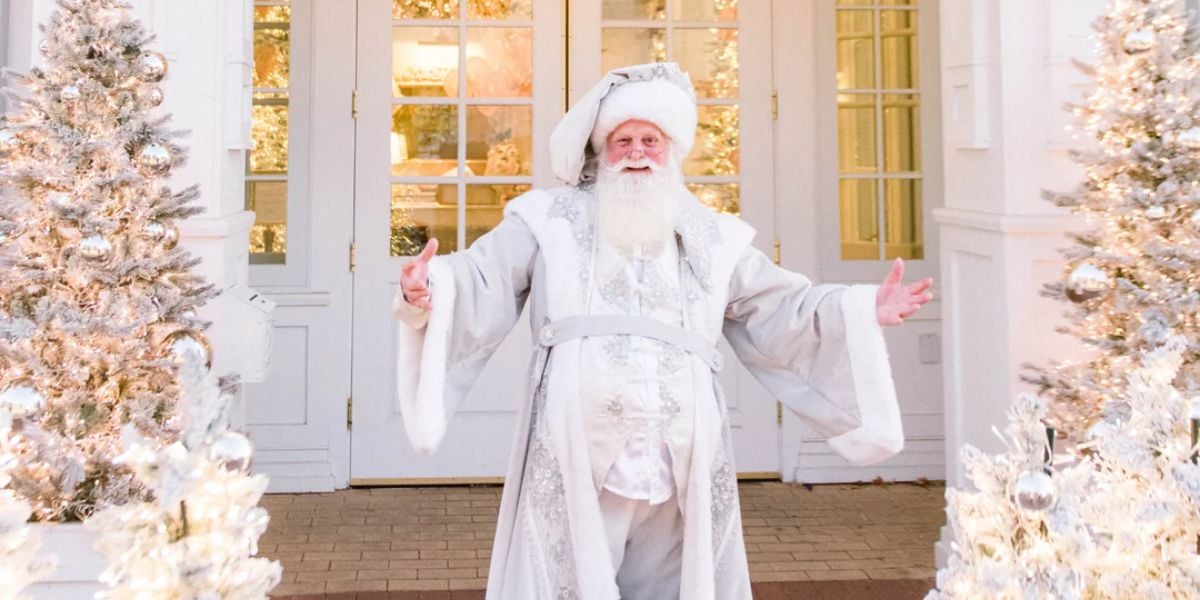 Santa Claus in a white outfit outside The Cake Bake Shop at Disney World