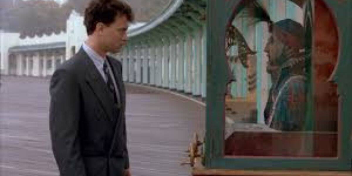 A man in a suit stands on a boardwalk, looking at a fortune-telling machine—famously featured in the filming location of Tom Hanks' classic Big, which was recently vandalized by a group of young men.