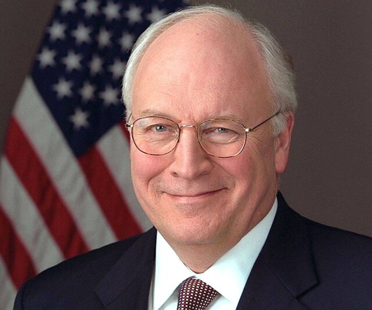 Dick Cheney smiles in front of an American flag