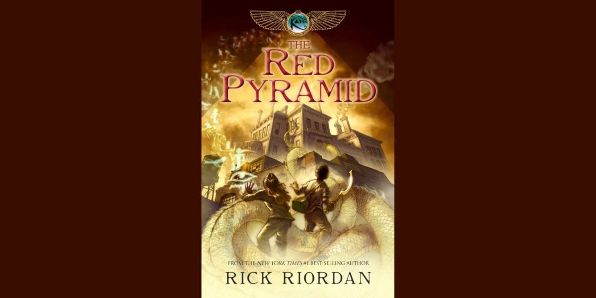 Book cover of "The Red Pyramid" by Rick Riordan, creator of Percy Jackson, showing two kids facing a giant serpent before an ancient Egyptian city with a fiery sky and magical light. The title appears in large red letters at the top.