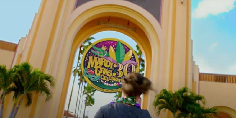 guest walks toward universal studios florida arch for mardi gras celebration