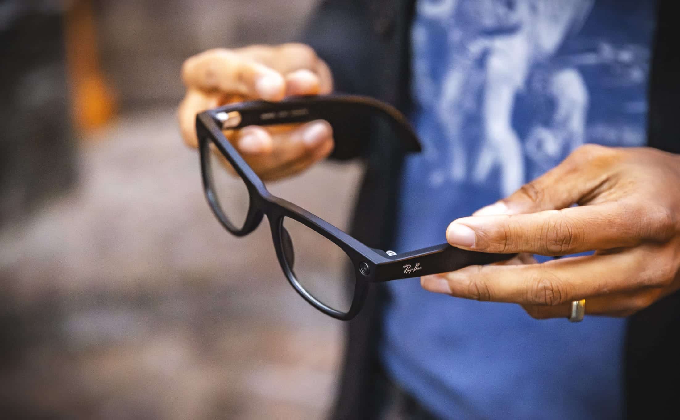 A guest at the park shows off their black Ray-Ban glasses, blue shirt, and a gold ring while enjoying the attractions.