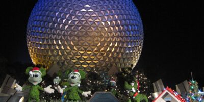 Mickey Mouse topiaries in Santa hats in front of Spaceship Earth in EPCOT during Christmas