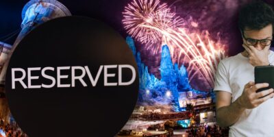 Enjoy exclusive Disney World Fireworks Viewing by Reservation as bursts light up the park, a guest checks their phone by a reserved sign.