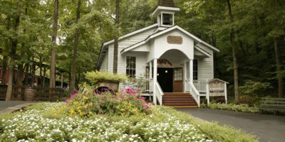 Charming park chapel nestled among lush gardens and blooms, with a whimsical "CHAPEL" sign welcoming guests at the entrance.