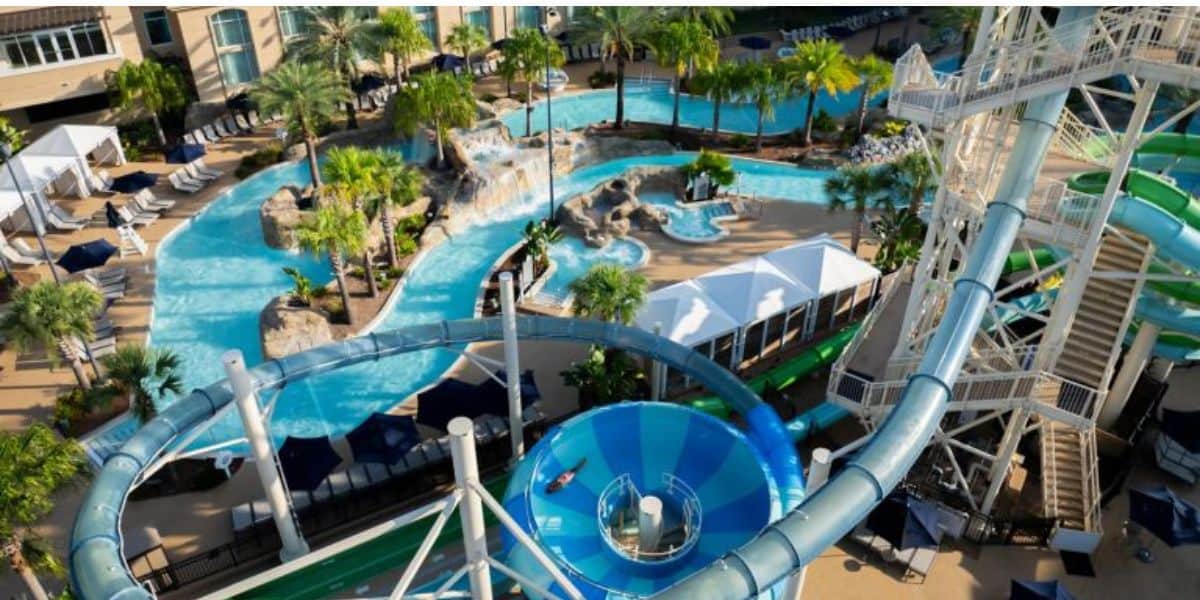 Water park at a luxury resort featuring winding slides, sparkling pools, cabanas, palm trees, and plenty of lounge seating.
