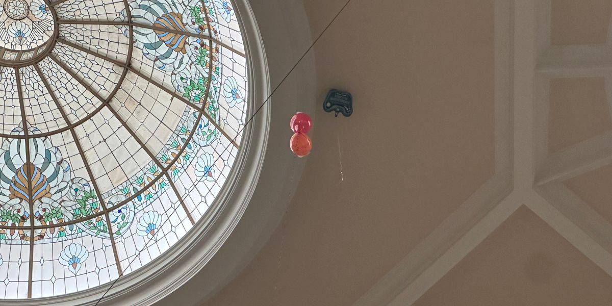 Stained glass dome at Disney’s Grand Floridian with whimsical Balloon Rescue details: hanging balls and toy car beneath.